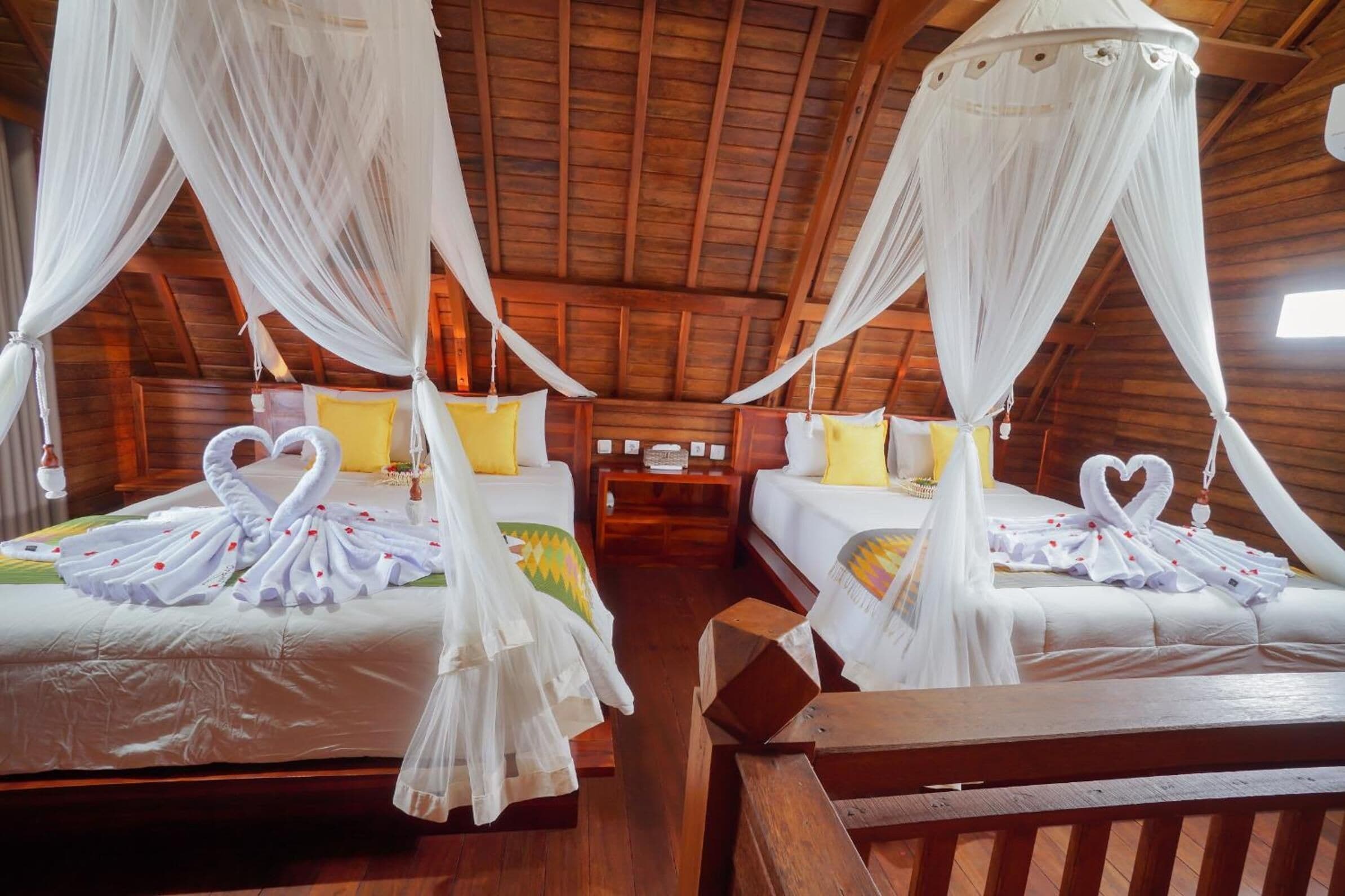 A room with two beds, each with white bedding and decorative swan-shaped pillows.