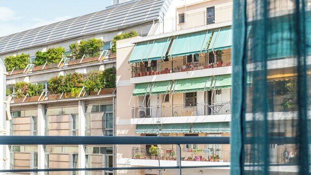 A balcony with a table and two chairs, overlooking a residential area with multiple buildings. - Elvita Apartments 2 (Athens)