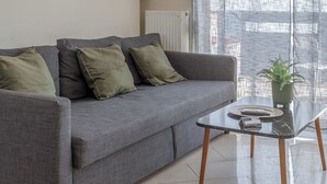 A modern living room with a grey sofa, green cushions, a glass coffee table, and a decorative wall piece. - Elvita Apartments 2 (Athens)