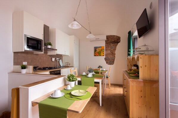 Una cocina moderna con armarios blancos, un microondas y una mesa de comedor de madera con manteles individuales verdes.