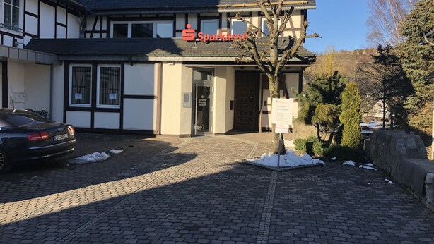 Un edificio con un cartello che riporta "Sparkasse" e un'indicazione per l'area di parcheggio clienti.