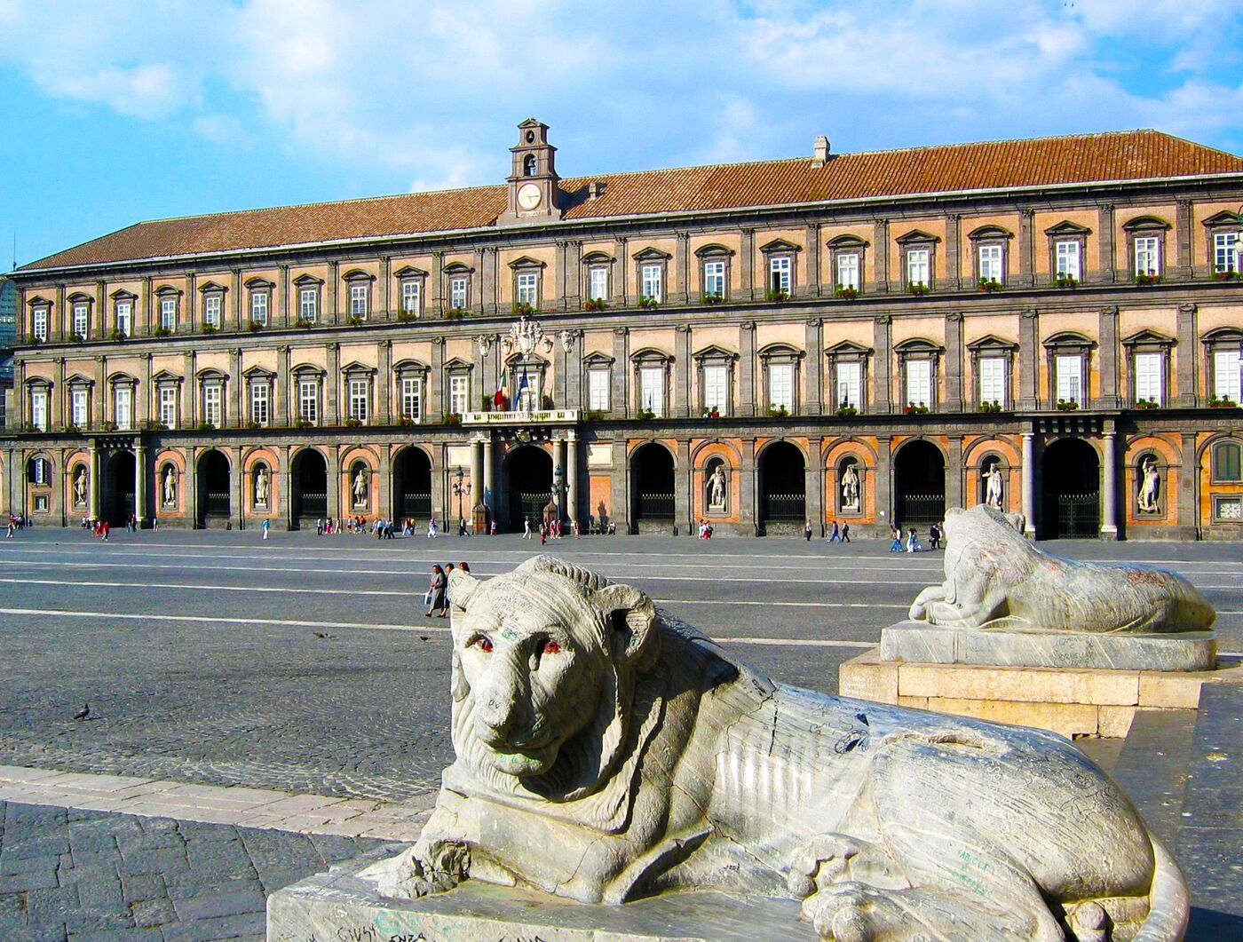 A historic building with classical architecture, featuring a central courtyard with statues and a clock tower.