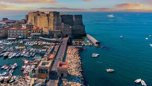 A coastal town with a historic castle, a marina with numerous boats, and a rocky waterfront. - Donna Lena Relais (Naples)