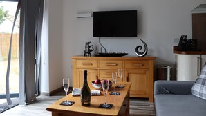 Ein modernes Wohnzimmer mit einem Holztisch, einem an der Wand befestigten Fernseher und einem Sofa.