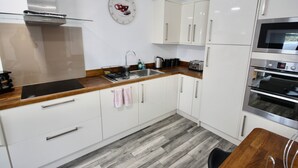 Eine moderne Küche mit weißen Schränken, einer Edelstahl-Dunstabzugshaube, einem Einbauofen und einer Holz Arbeitsplatte.