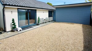 Ein Haus mit Ziegeldach, Schiebeglastür, Kiesweg und einer blauen Garagentür.