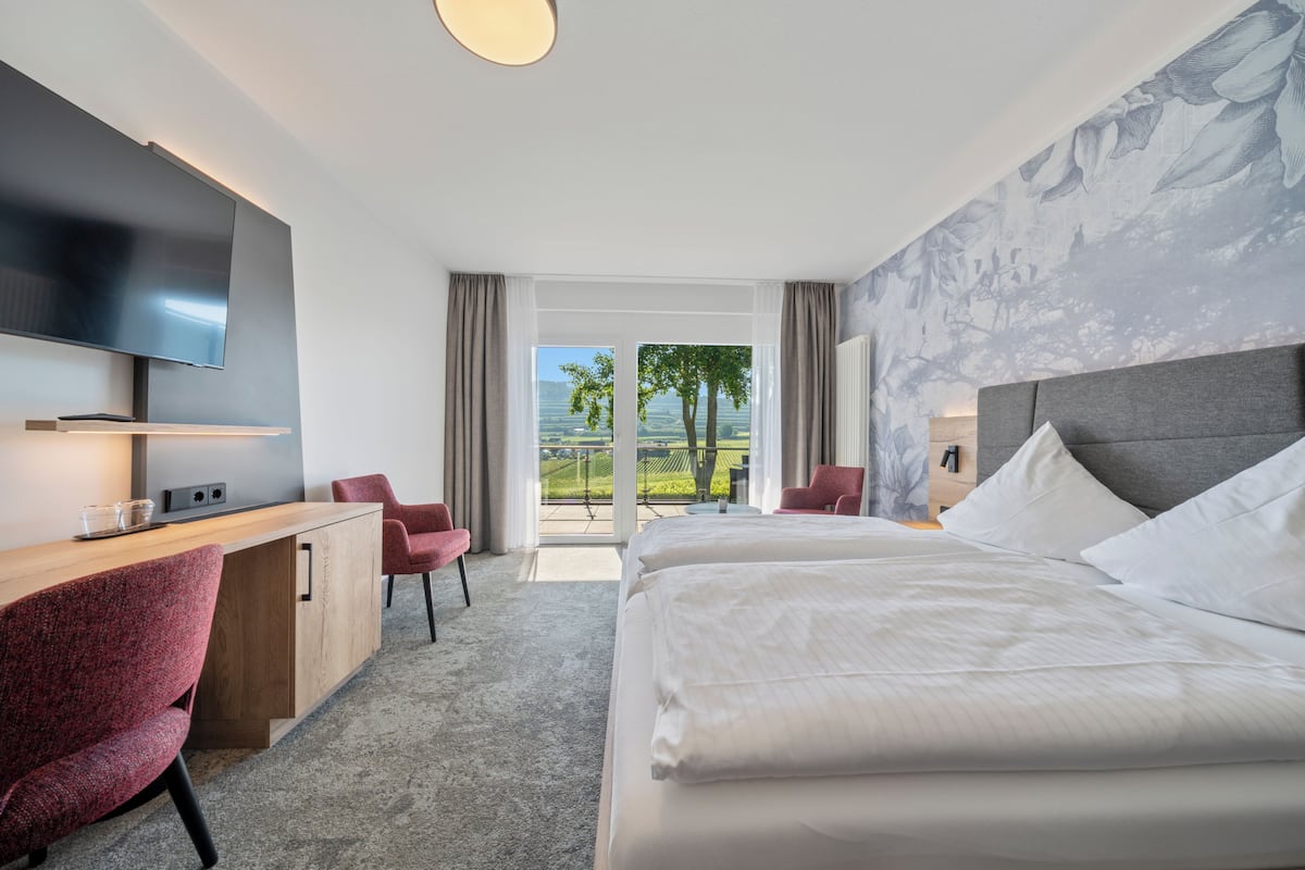 Een hotelkamer met een groot bed, een bureau met stoel, een flatscreen-tv en uitzicht op het omliggende landschap.