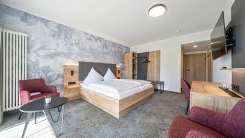 A modern hotel room with a large bed, a desk, a chair, and a TV.