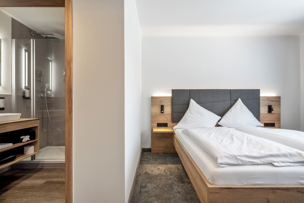 Een moderne slaapkamer met een houten bed, nachtkastjes, een inloopdouche en een grote spiegel.