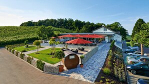 A hotel with outdoor seating, a stone barrel, and a parking lot.