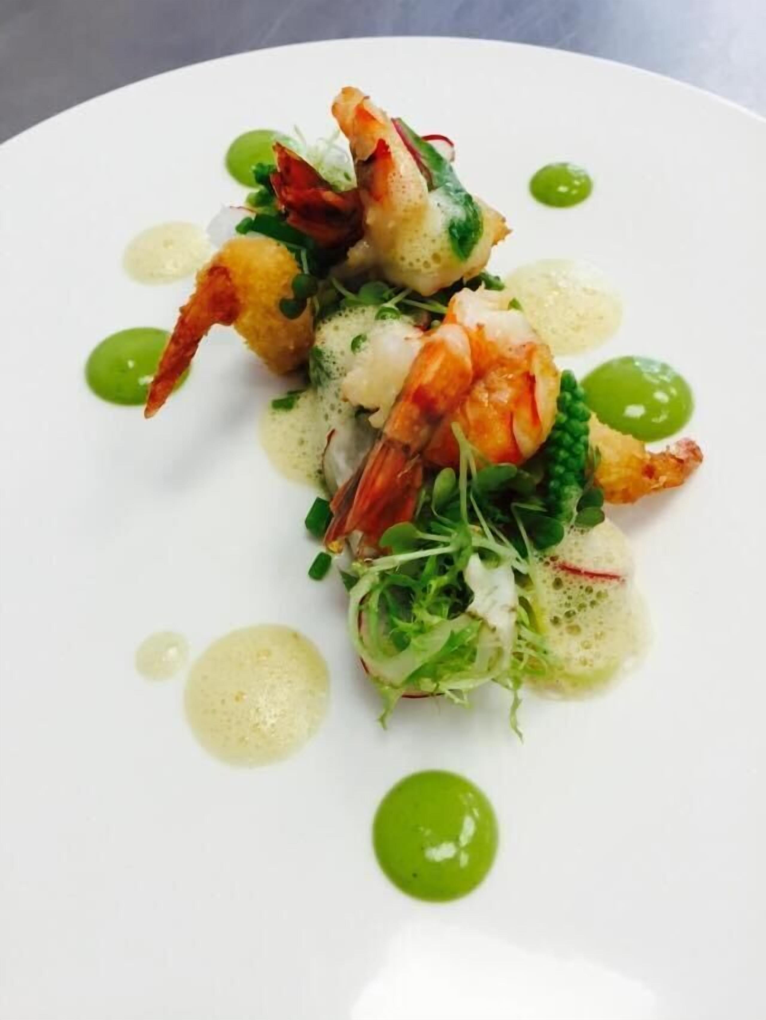 Une assiette de nourriture contenant des crevettes et des légumes verts.