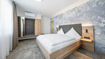 A modern hotel room with a wooden bed, a built-in wardrobe, and a floral wallpaper.