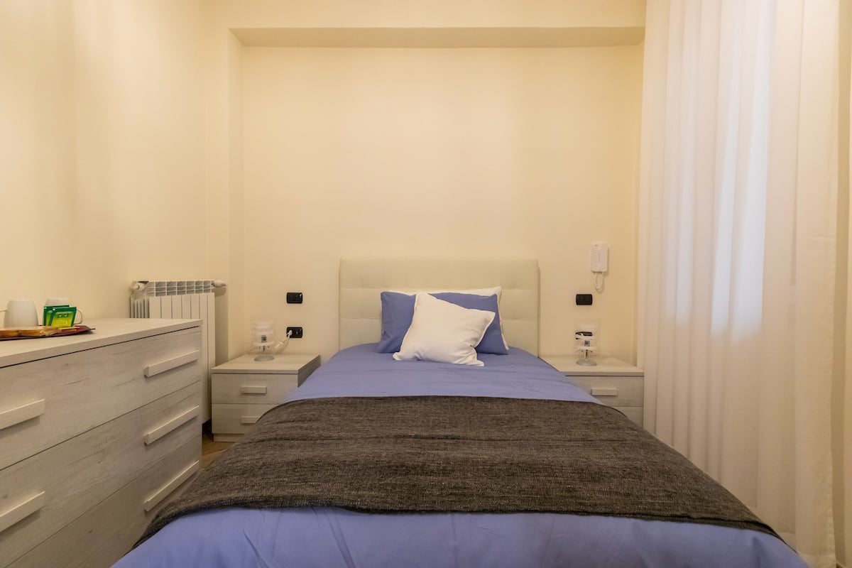 Un dormitorio con cama, mesitas de noche, cómoda y radiador.