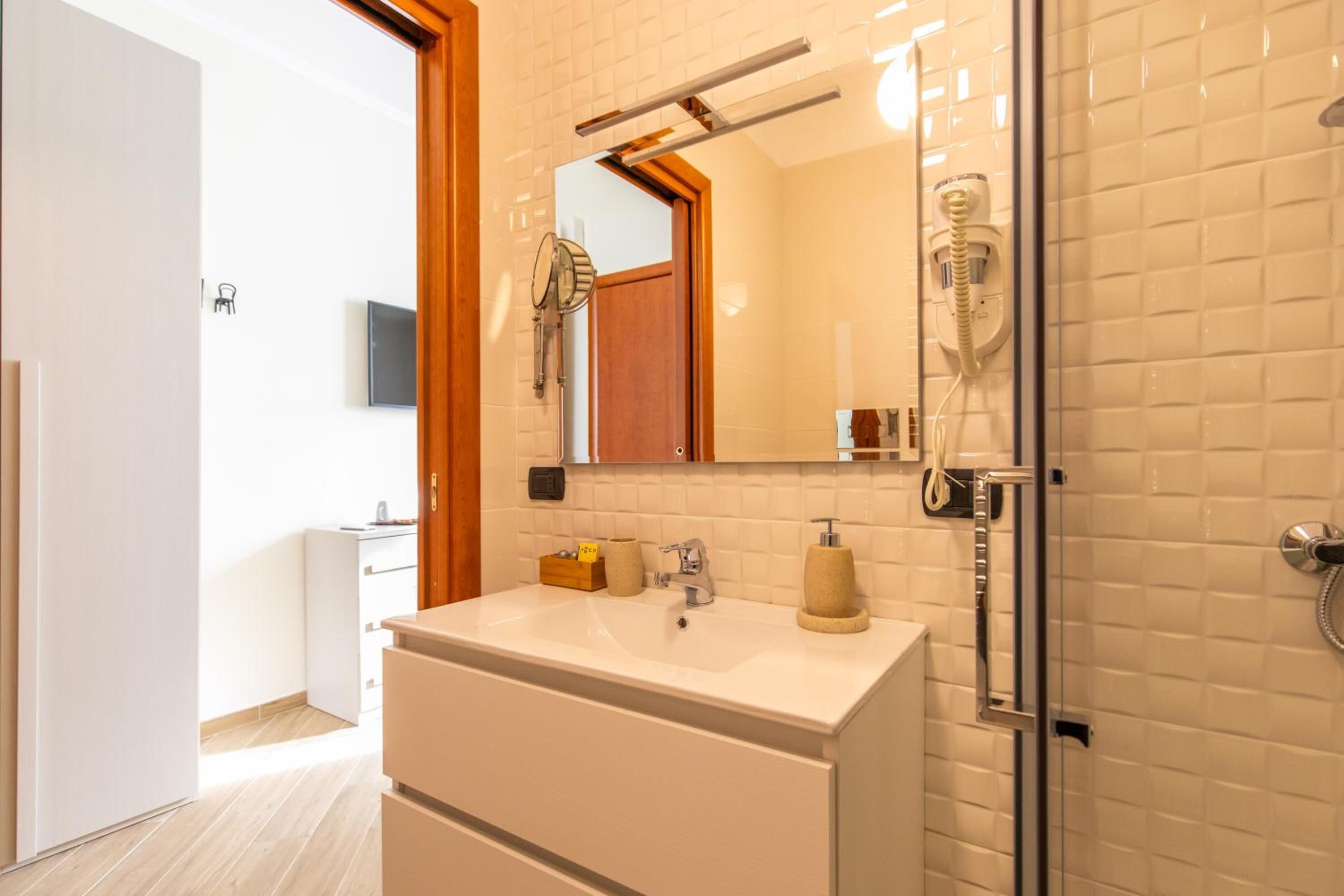 A modern bathroom with a white sink, a mirror, and a glass shower enclosure.