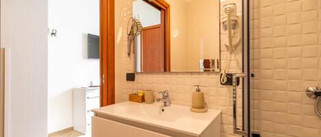 A modern bathroom with a white sink, a mirror, and a glass shower enclosure.