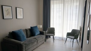 A modern living room with a grey sofa, two armchairs, and a coffee table. There are two framed artworks on the wall and a floor lamp. - Re di Smirne (Bari)