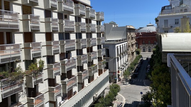 A multi-story residential building with balconies, a street view, and a historic building in the background. - Re di Smirne (Bari)