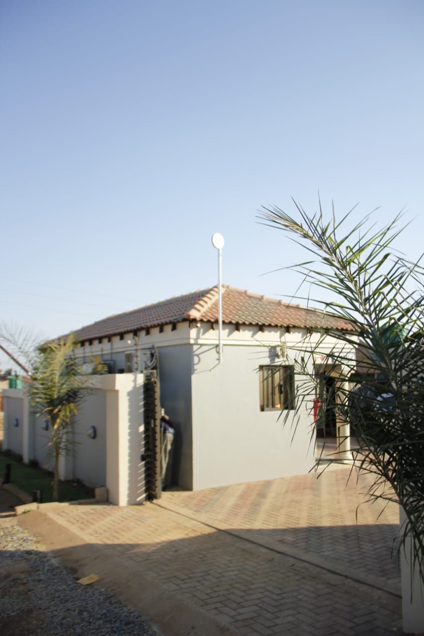 A single-story building with a tiled roof, a small porch area, and a satellite dish.