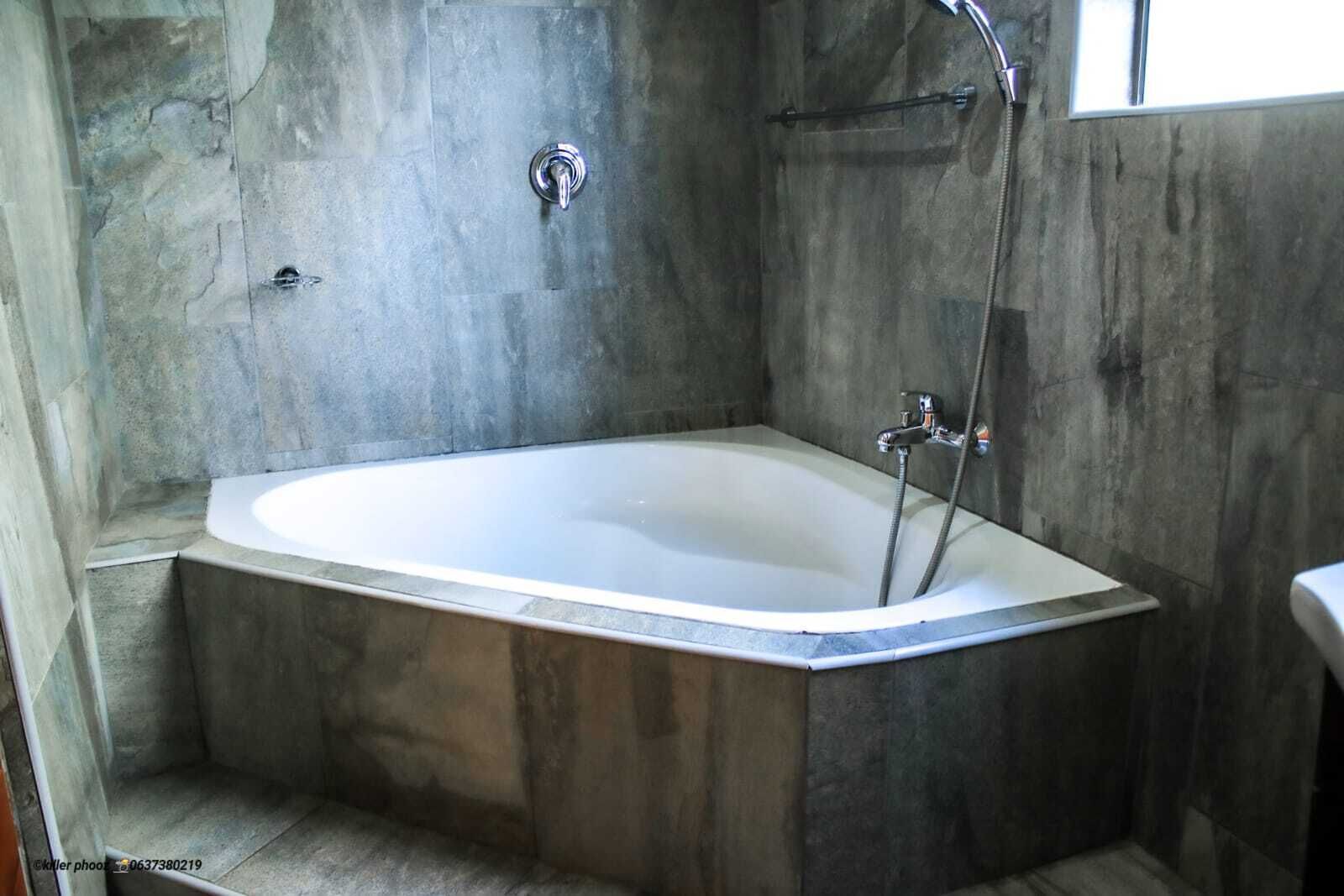 Un baño moderno con una bañera independiente, zona de ducha y ventana visible.