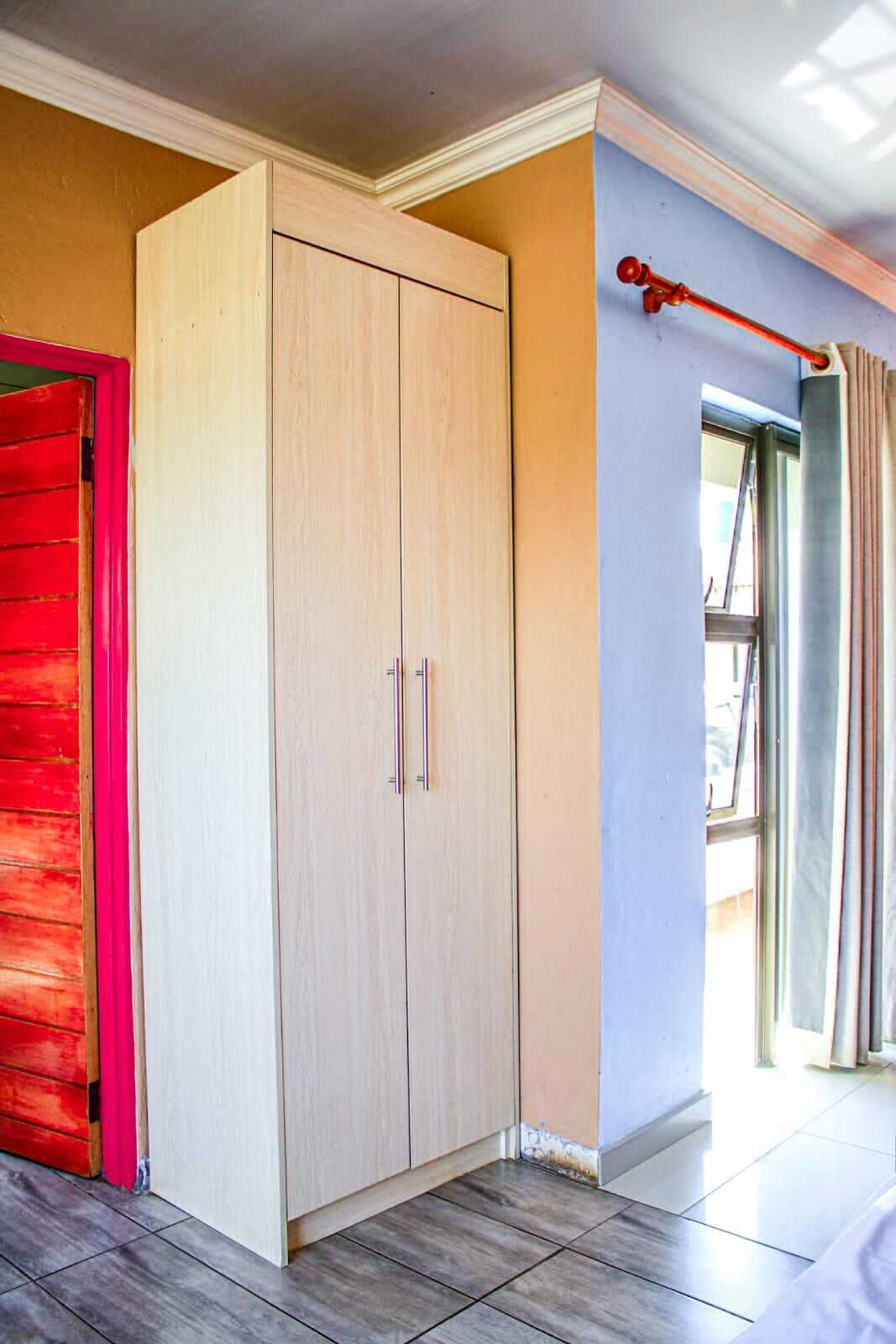Una habitación con un armario grande, una puerta roja y una ventana con cortinas.