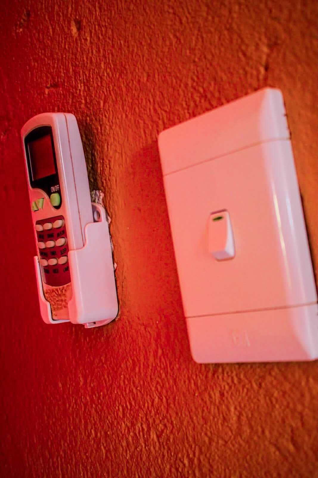A white portable heater and a white electronic device on a red surface.