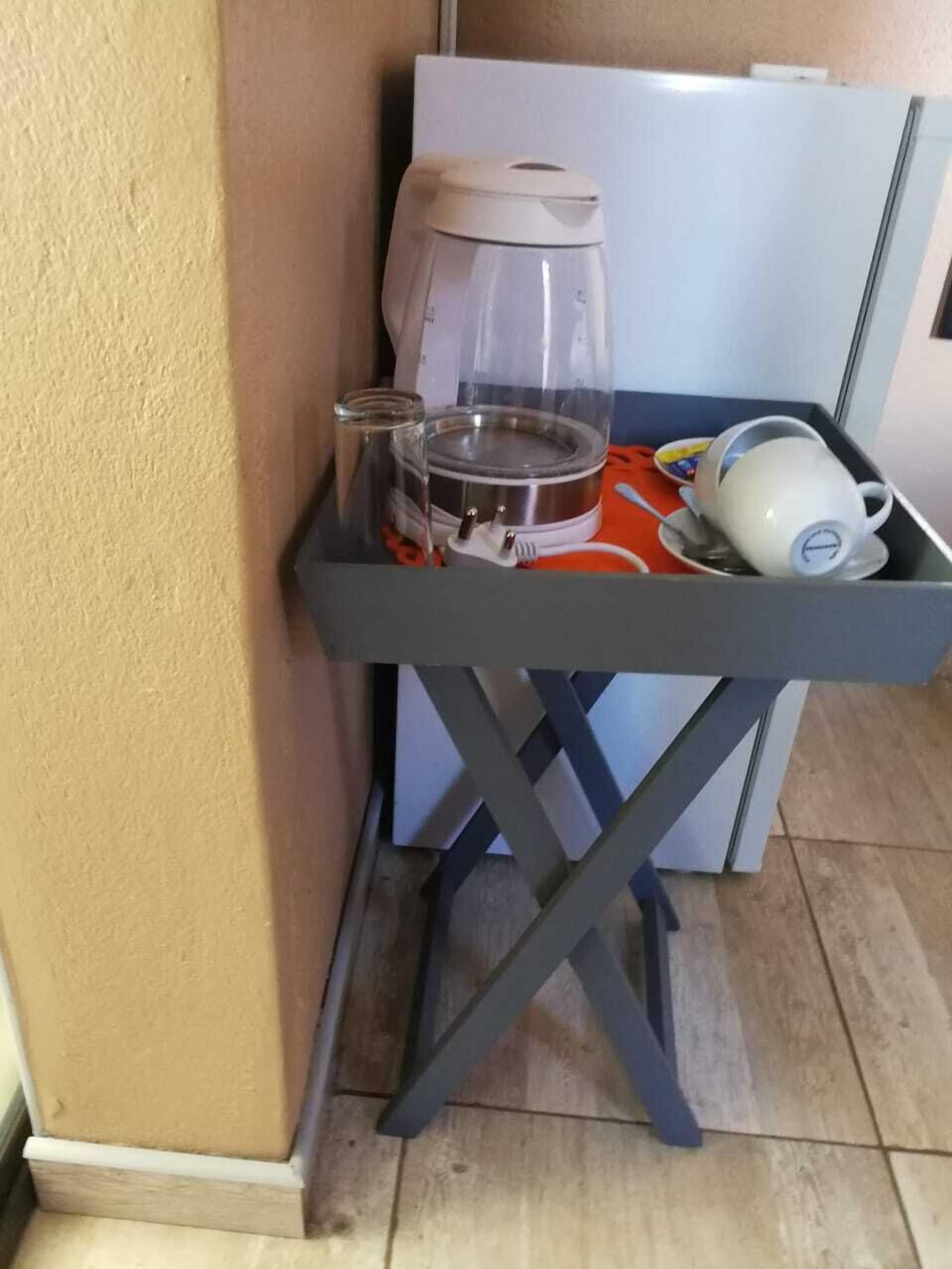 A kitchenette with a coffee maker, a kettle, and a microwave on a small table.