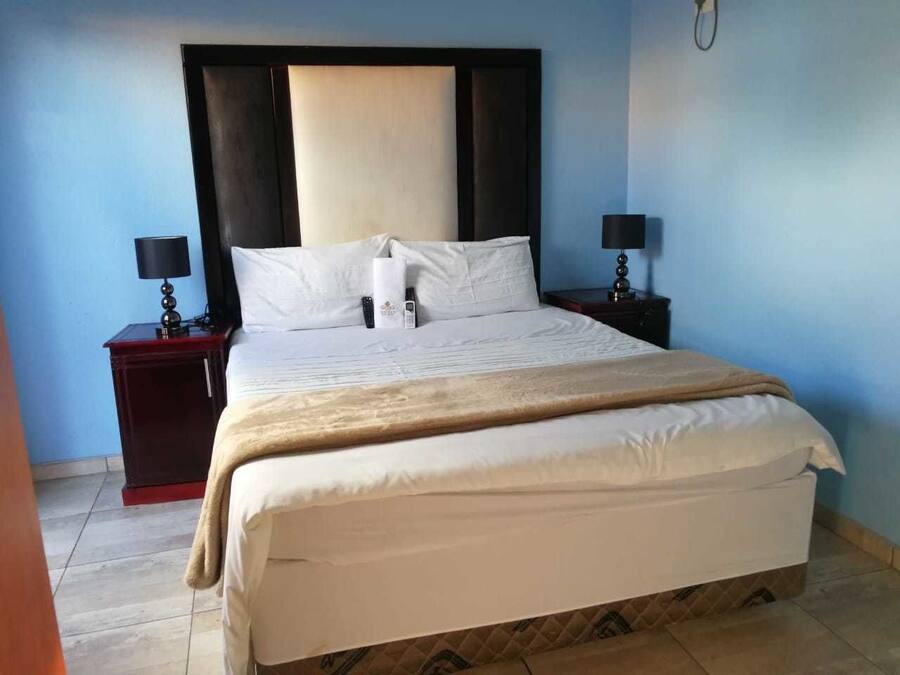 A hotel room with a large bed, two bedside tables with lamps, and a headboard.