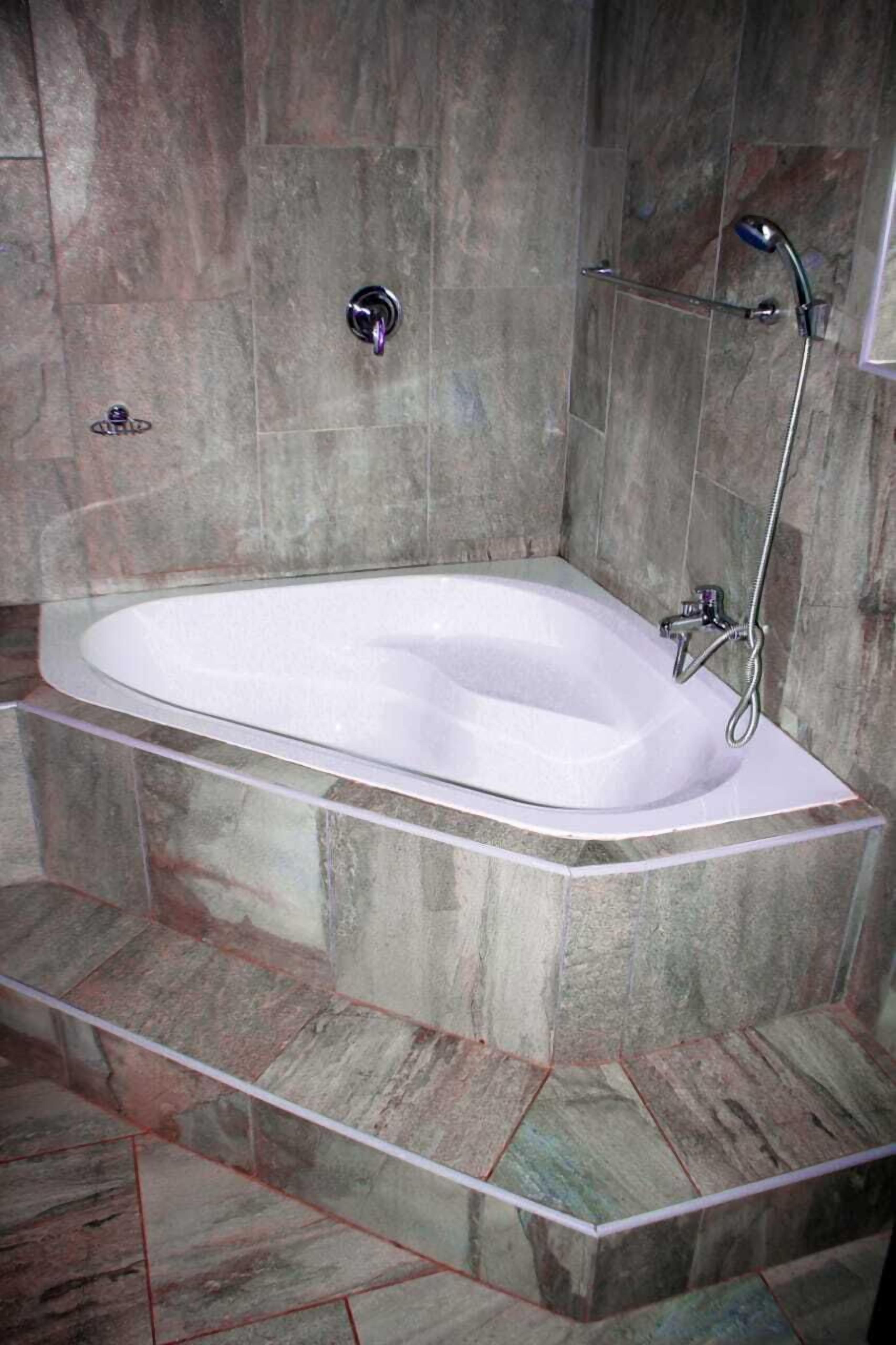 A modern bathroom with a freestanding bathtub, a handheld showerhead, and a wall-mounted faucet.
