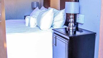 Une chambre d’hôtel avec un lit, une table de chevet avec une lampe et un miroir fixé au mur.