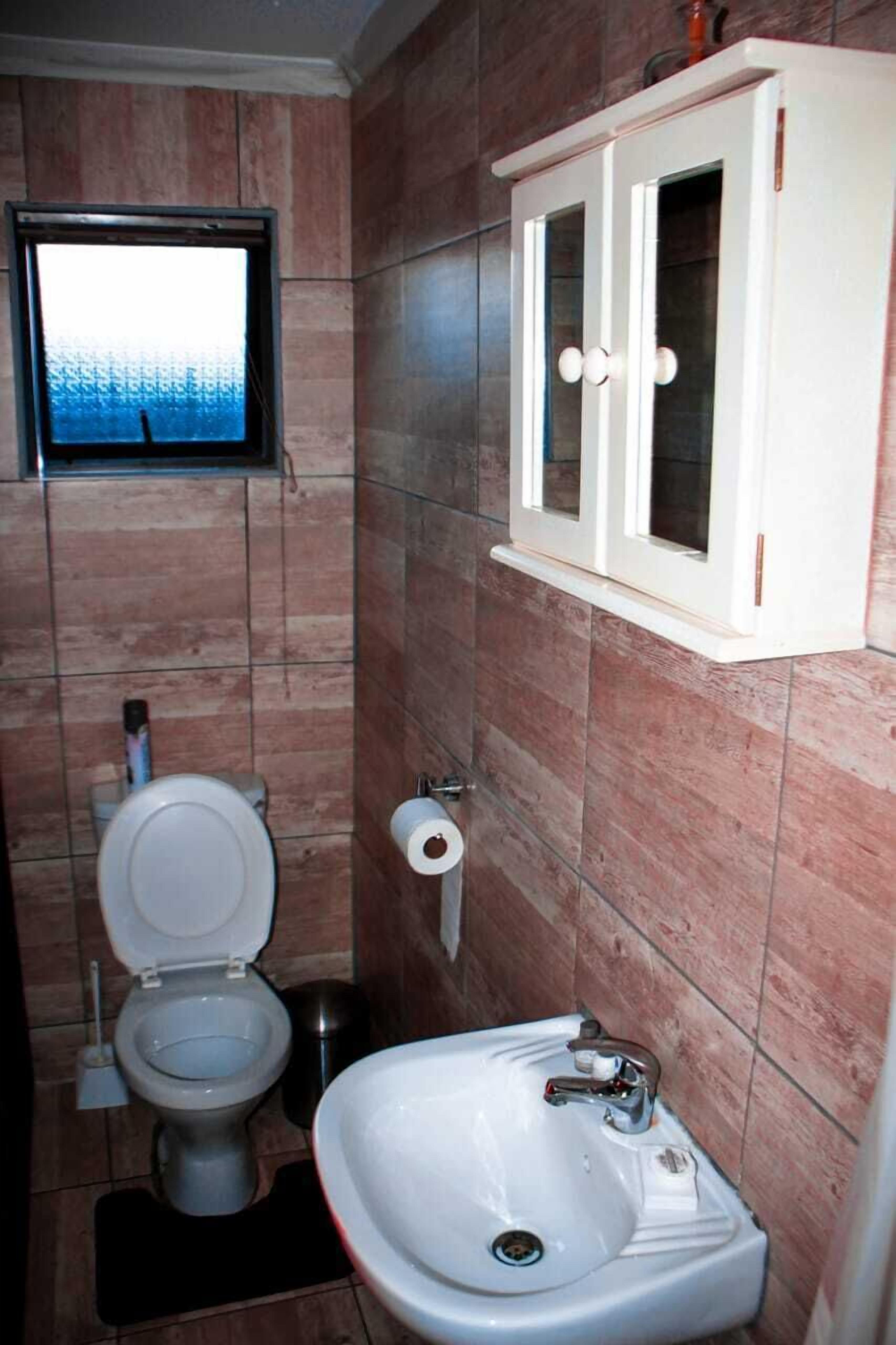 A bathroom with a toilet, sink, and cabinet.
