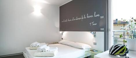 Una habitación de hotel moderna con una cama, una mesita de vidrio, un casco de bicicleta y una cita en la pared.