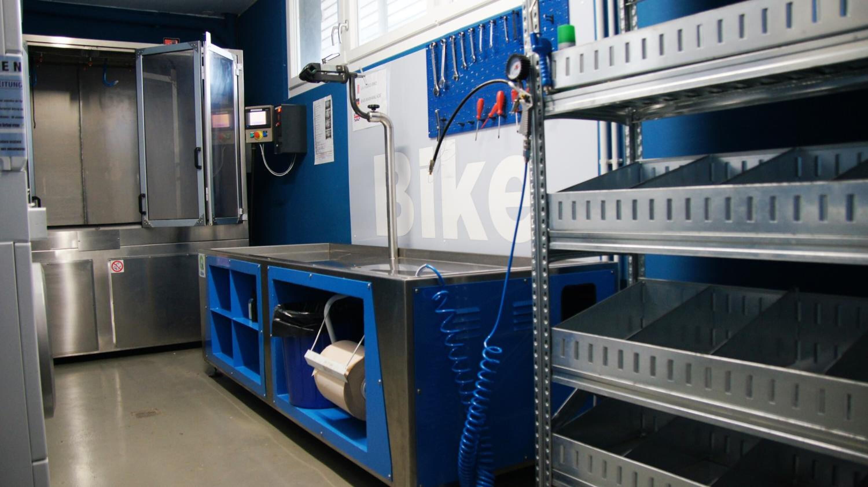 Een schone, industrieel ingerichte ruimte met metalen schappen, een wastafel en een bedieningspaneel.