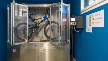 Estação de lavagem de bicicletas com parede azul e painel de controle.
