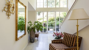 A spacious hallway with a large mirror, a potted plant, a sofa, and a lamp. - Boutiquehotel Bergvilla (Zwischenwasser)
