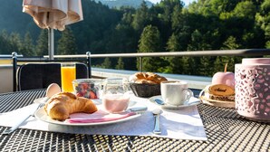 A breakfast setup on an outdoor table with croissants, a glass of orange juice, a bowl of yogurt, and a pink mug. - Boutiquehotel Bergvilla (Zwischenwasser)