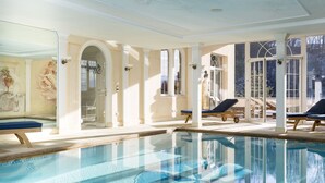 A large indoor swimming pool with lounge chairs and a glass wall. - Boutiquehotel Bergvilla (Zwischenwasser)