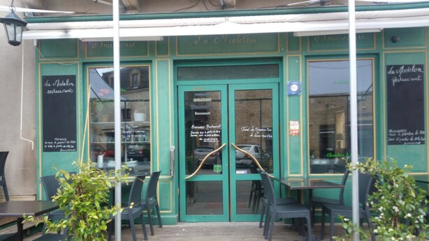 A restaurant with outdoor seating, green doors, and a chalkboard menu. - Le Madelon (Pays-de-Belves)