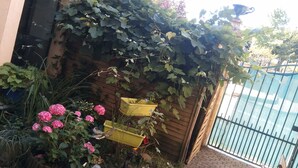 A garden area with a wooden fence, potted plants, and a yellow planter box. - Le Madelon (Pays-de-Belves)