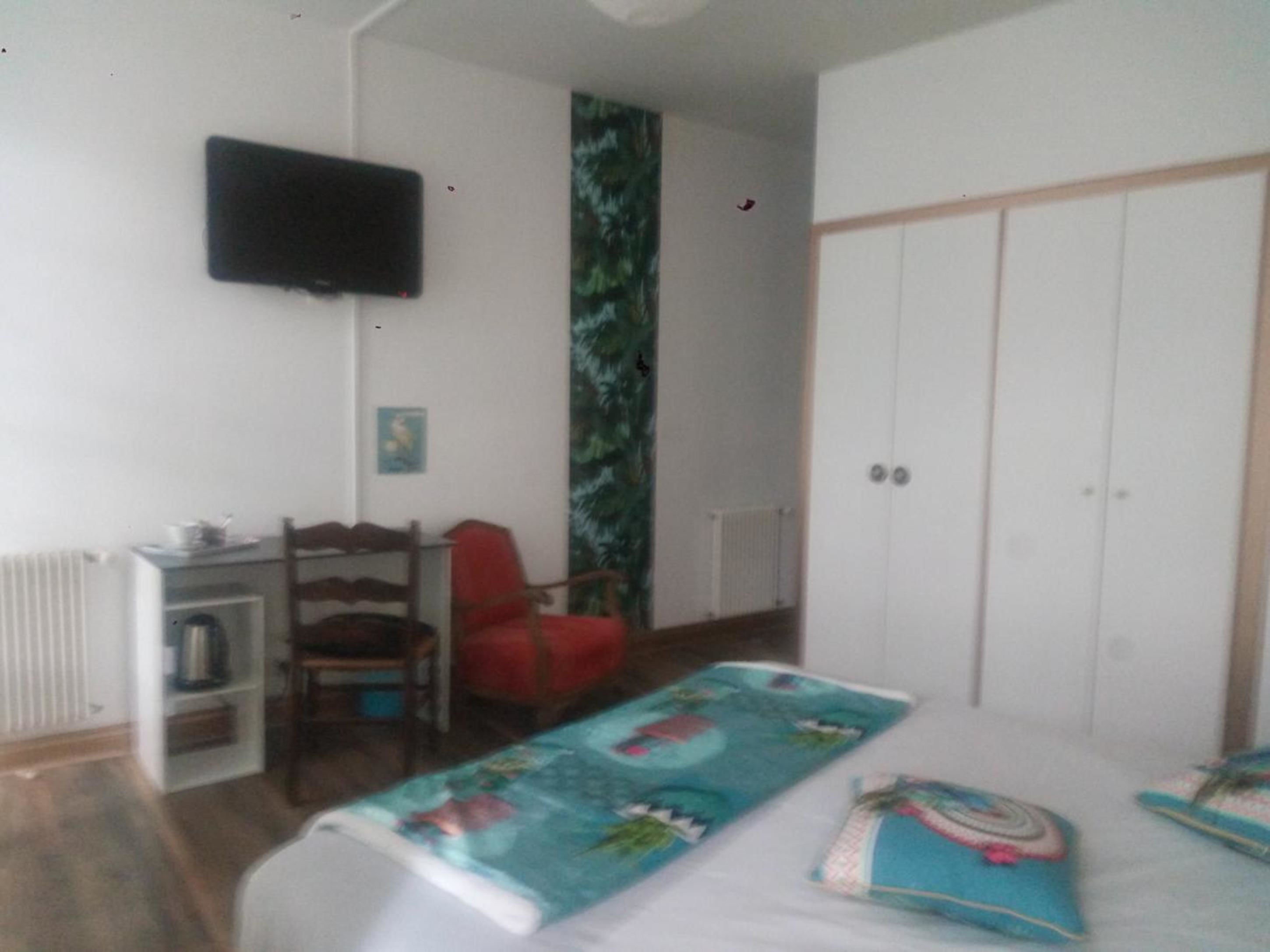 A room with a bed, a desk with a chair, a television, and a wardrobe.