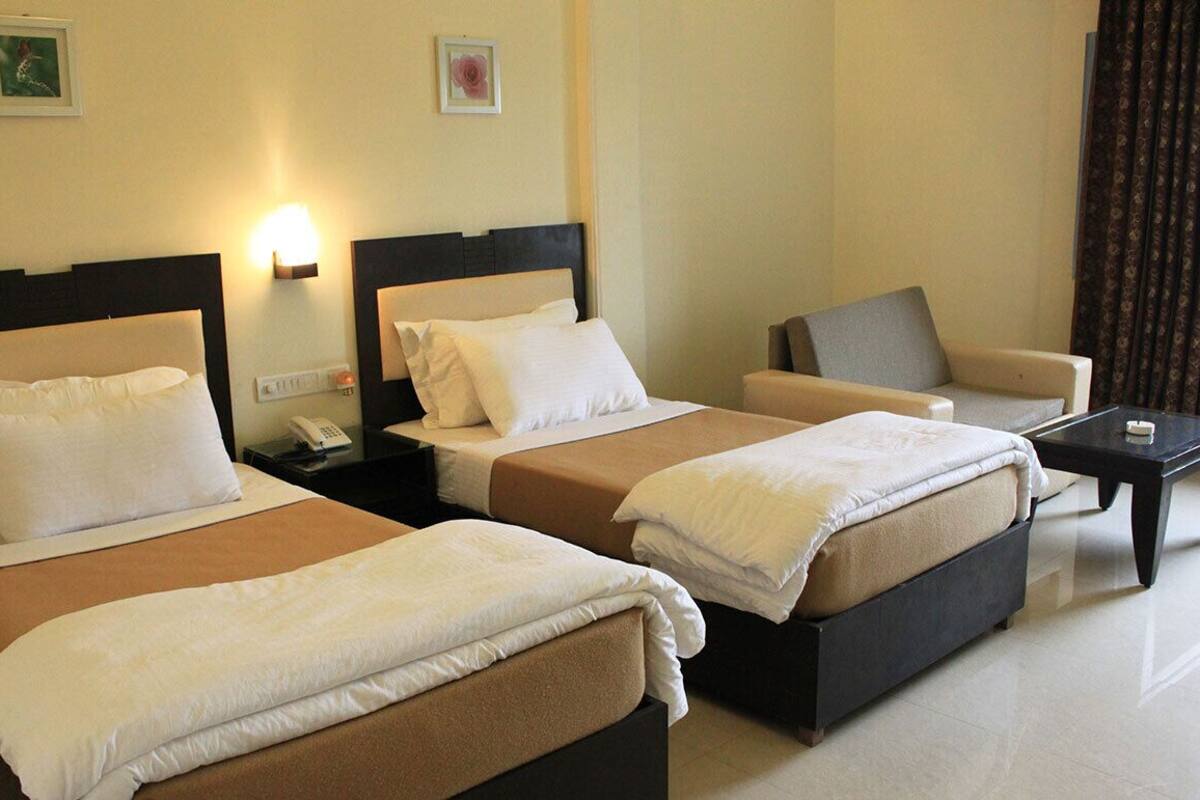 A hotel room with two beds, a sofa, a nightstand with a phone, and a small table.