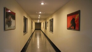 Un pasillo largo y estrecho con suelo pulido y cuadros enmarcados en las paredes.