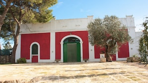 Un edificio con fachada roja y blanca, una puerta verde y un patio de piedra.