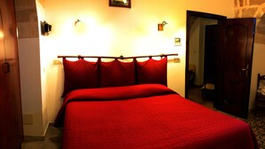 Una habitación de hotel con una cama grande, cabecero de madera y una puerta que da a otra habitación.