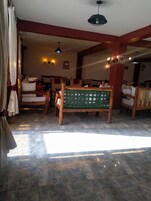 Habitación de hotel con una cama de madera, un banco verde y suelo de baldosas.