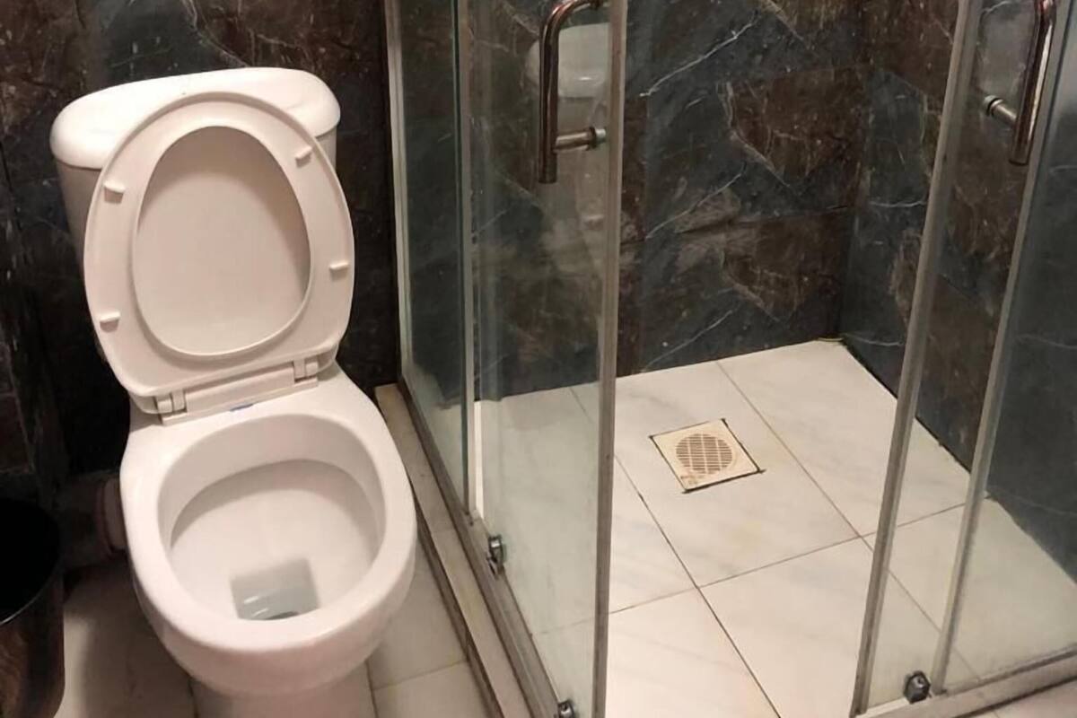 A bathroom with a toilet, shower, and glass-enclosed shower stall.