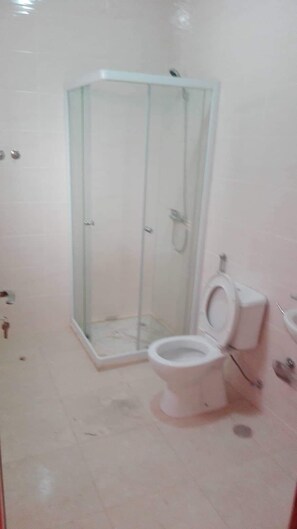 A bathroom with a glass-enclosed shower, a toilet, and a sink. - Appartement Bela Vista (São Vicente)