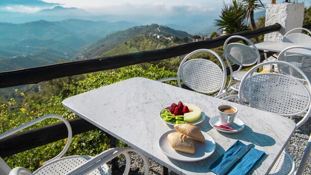 A table with a meal and a cup of coffee, overlooking a mountainous landscape. - Hotel Rural Los Caracoles (Torrox)