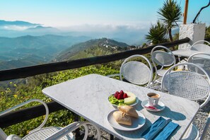 Una mesa con comida y una taza de café, con vistas a un paisaje montañoso.