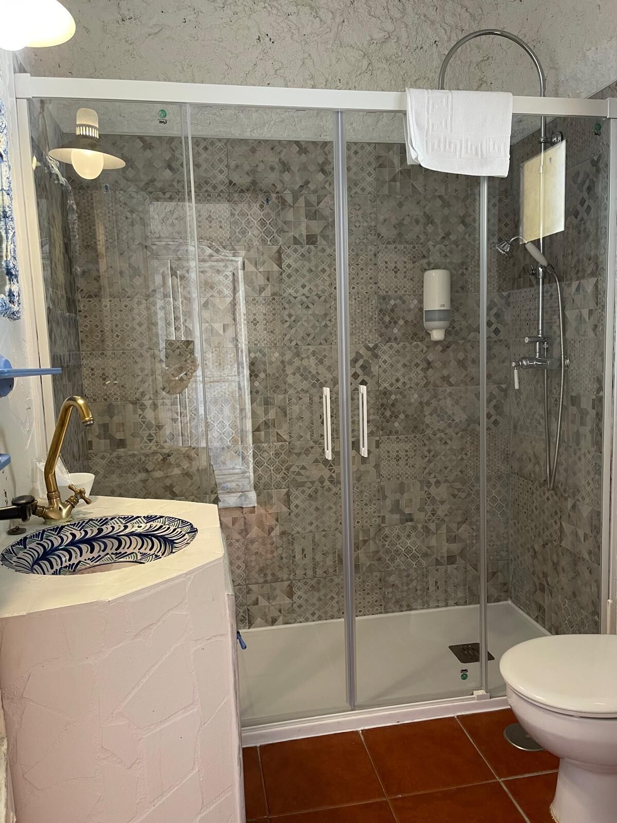 Une salle de bain avec une douche à parois de verre, un lavabo doté d’un receveur décoratif et des toilettes.