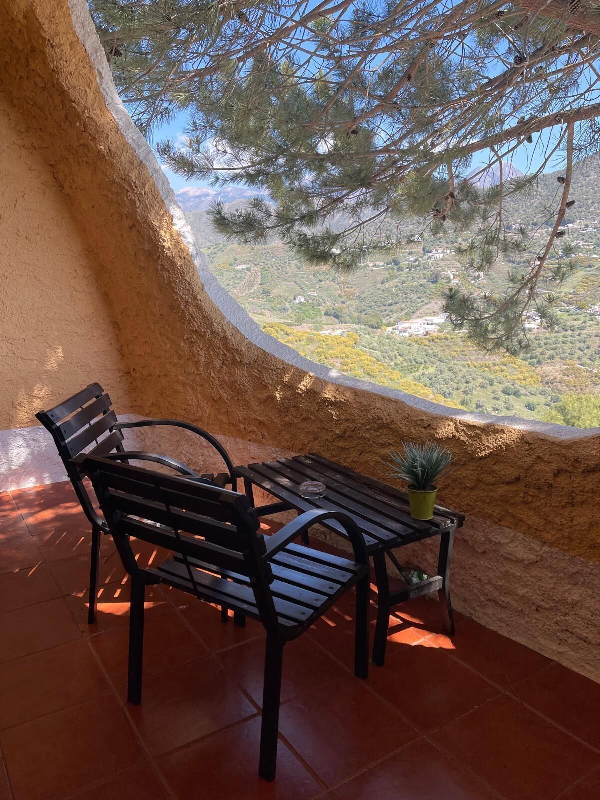 A bench and table inside a room with a view of a mountainous landscape.